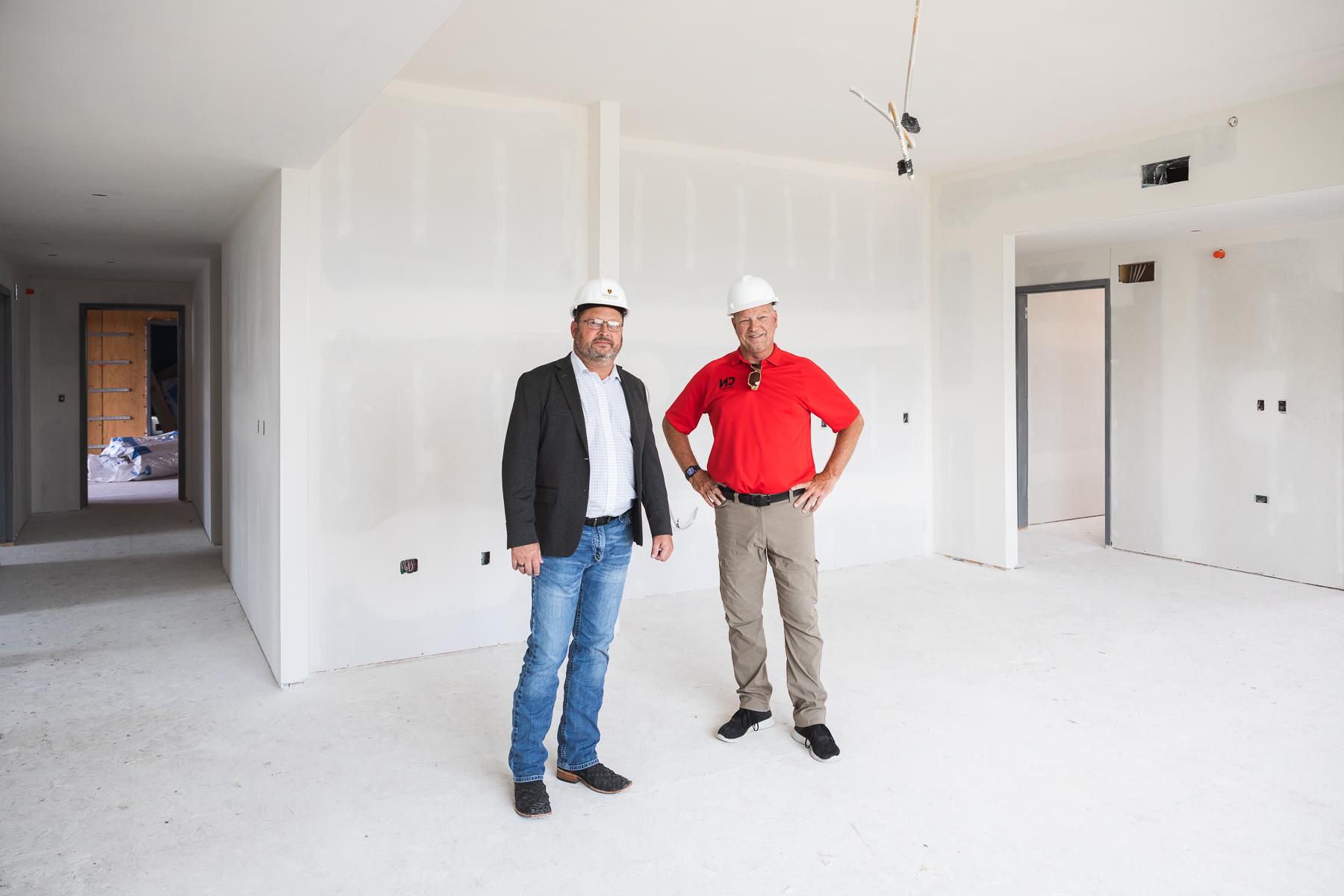Kevin Zadina, publisher of the Crete News, stands to the left of Brian Flesner during a tour for the news publication of Doane's new residence hall. The two stand in what will be the kitchenette and living space of one of the six eight-person suites located in the residence hall. 