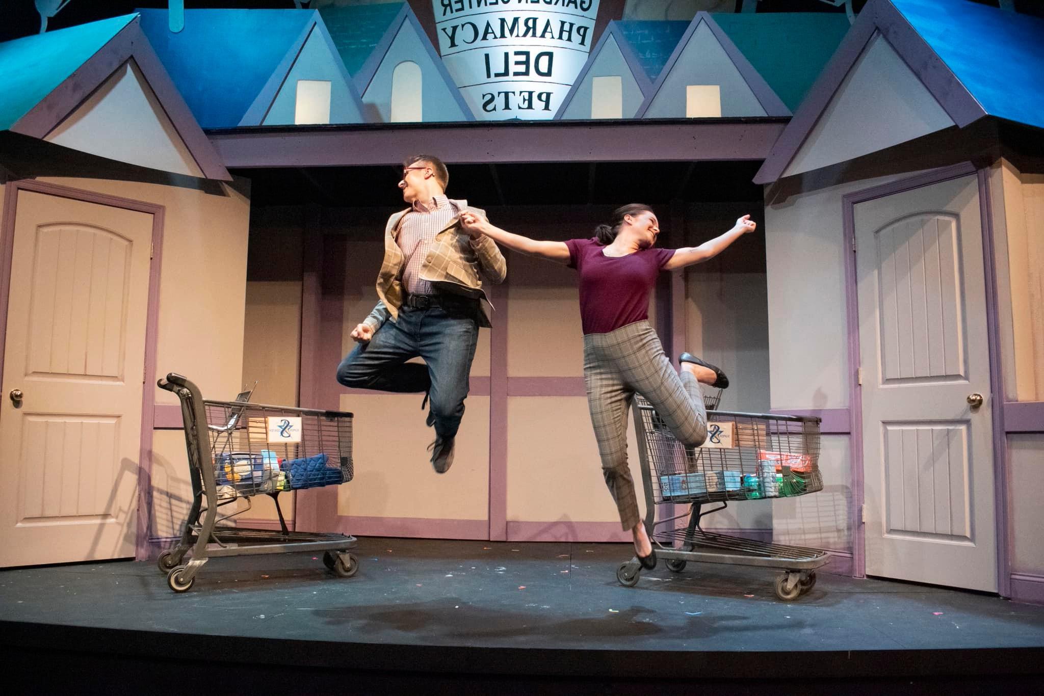 两个演员在舞台上跳向空中，看起来像一家杂货店, 两辆购物车，舞台左右两侧各有一扇门.