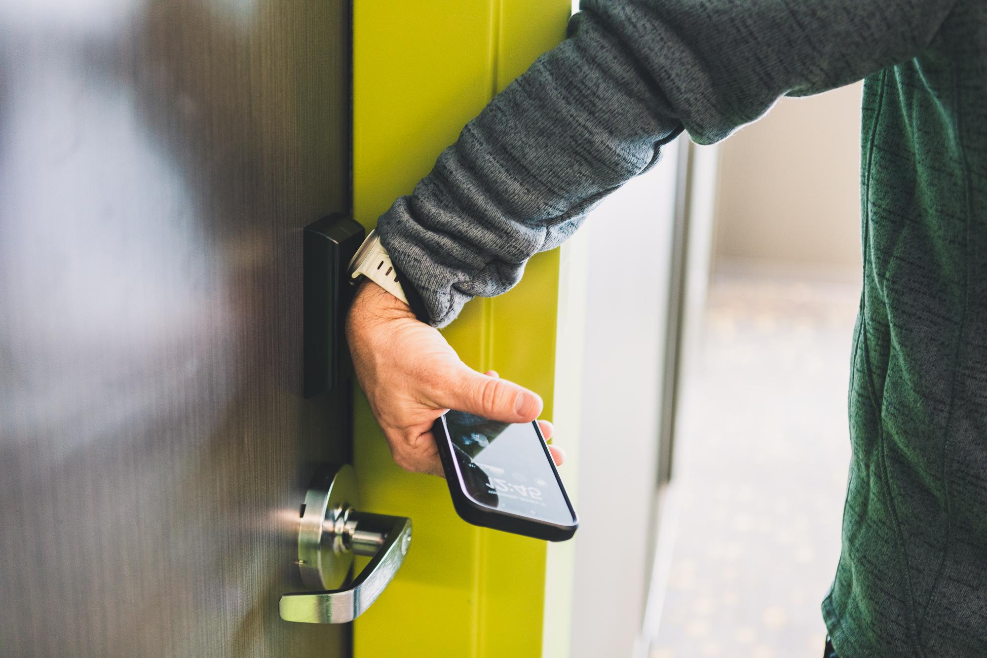 The New Hall is the first building on campus to feature electronic key entry. A man demonstrates how he uses his Apple Watch to unlock a door by placing it against a pad above the door handle.