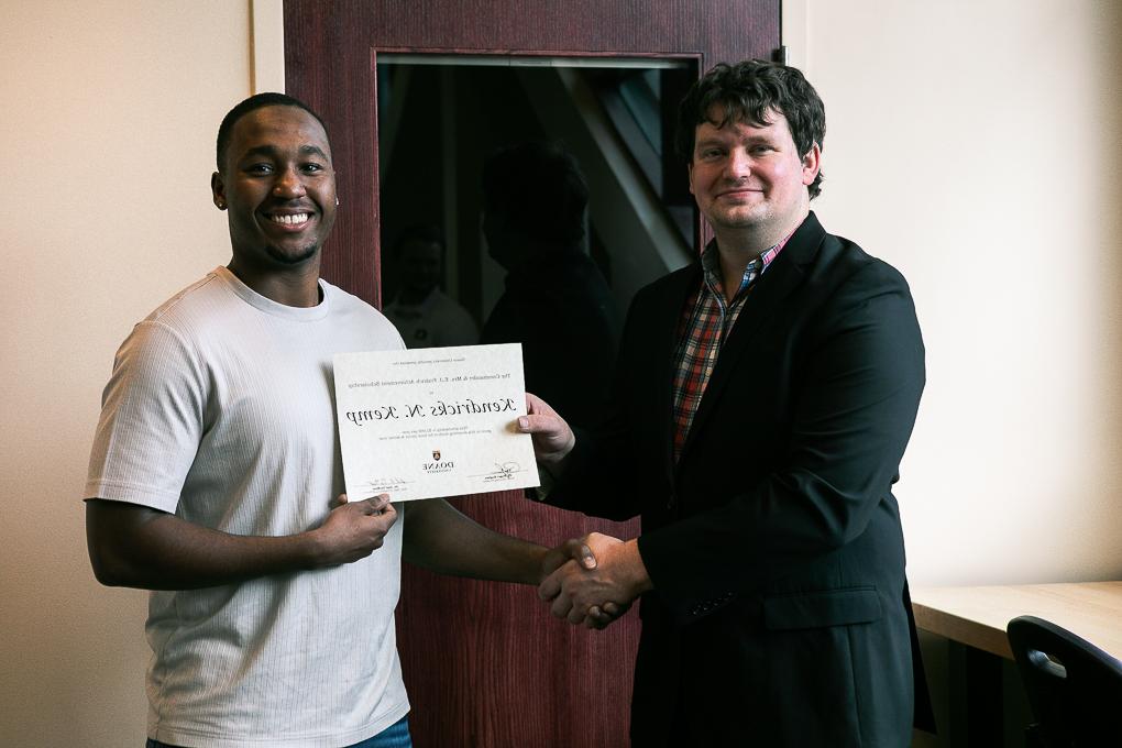 Senior engineering student Kenny Kemp holds up his scholarship while standing next to Dr. 凯尔Stolle.