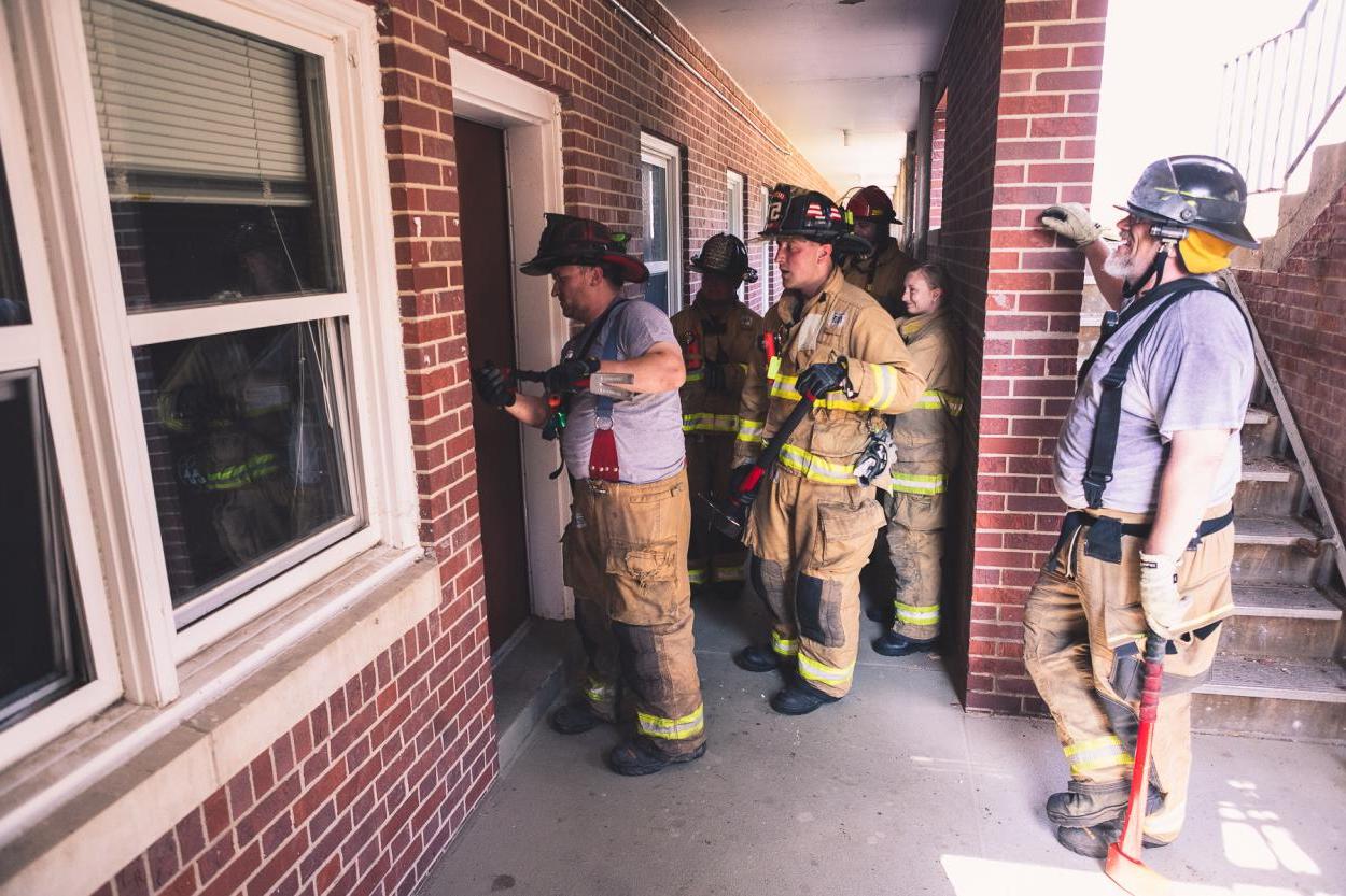 Firefighters watch a demonstration of breaking into a door outside of Burrage Hall. 