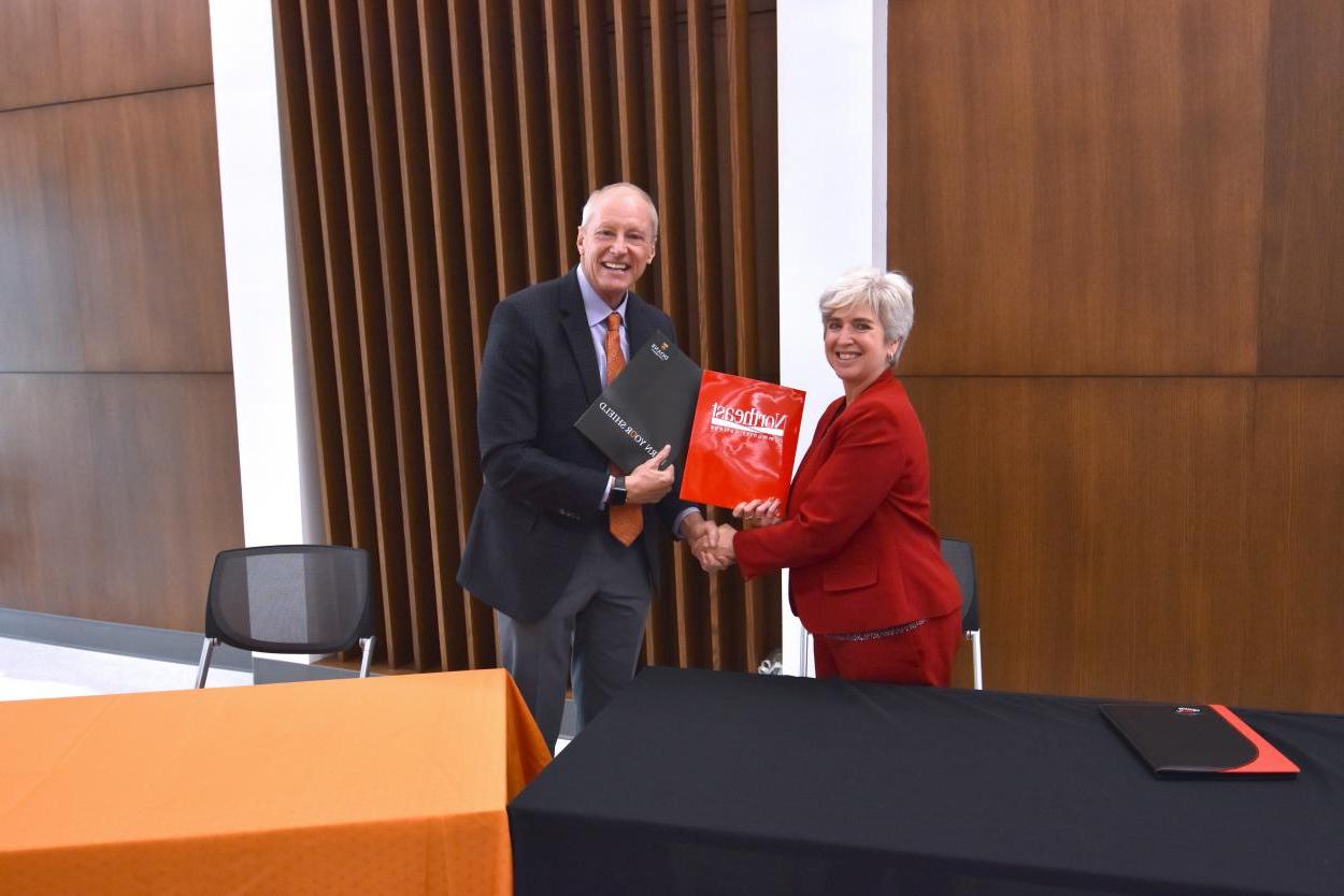 Dr. Leah Barrett, president of Northeast Community College, shakes hands with Dr. Roger Hughes, Doane president, after the two signed and institutional agreement Friday morning. 